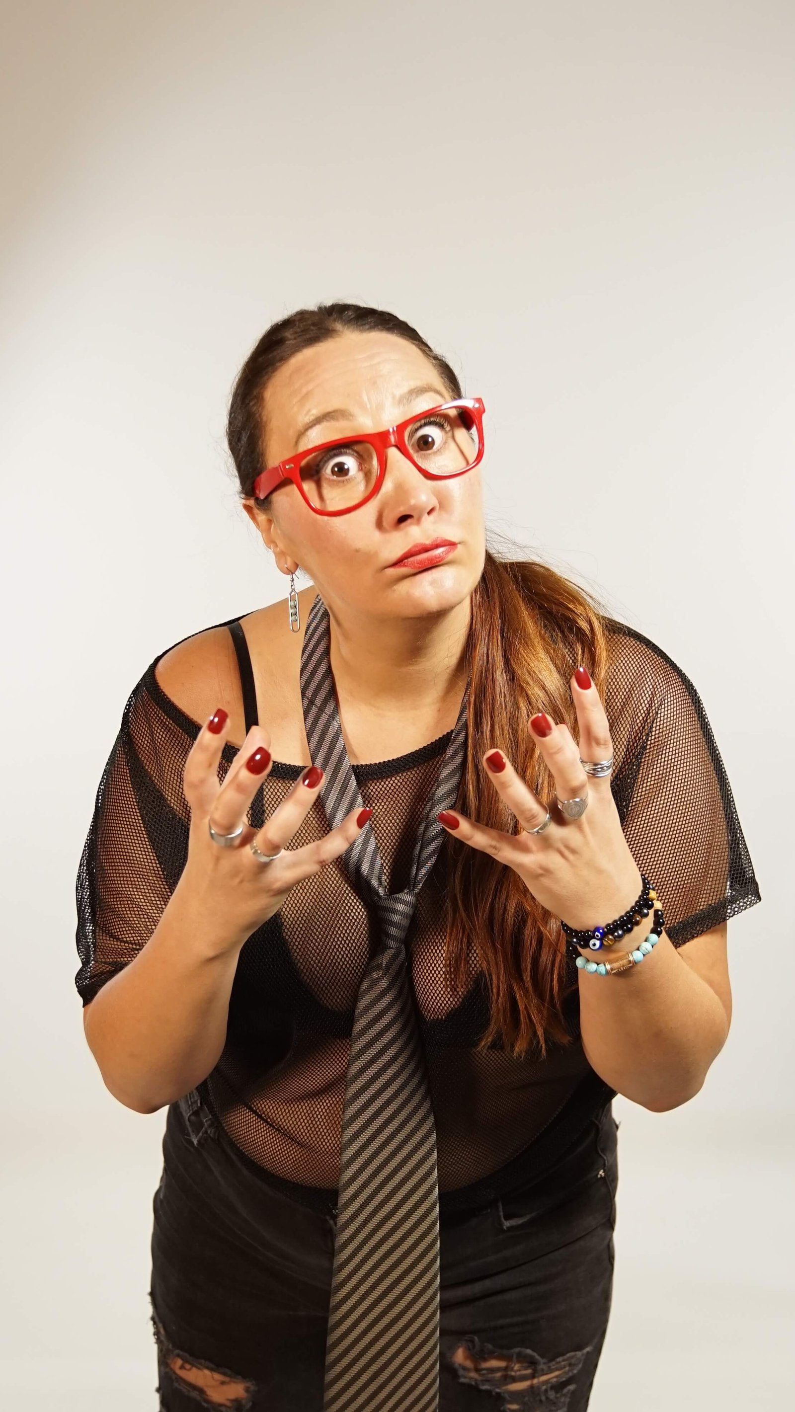 Eva riendo con gesto cómplice, gafas rojas, fondo neutro